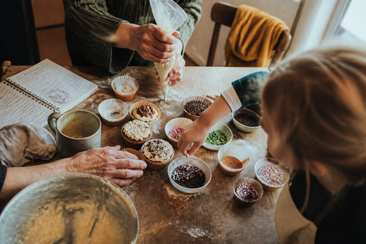 Atelier familial autour d’un plan de travail, mains de plusieurs générations.